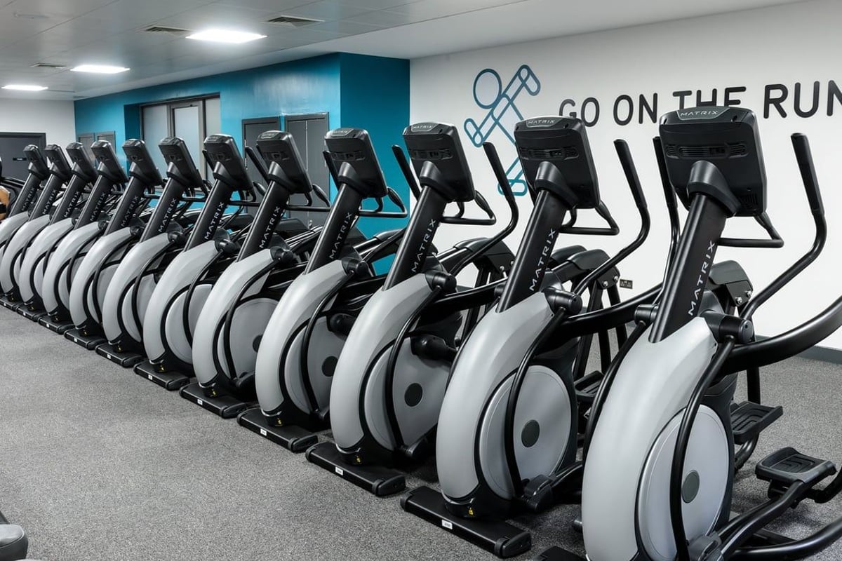 PureGym Glasgow Hope Street: Rows of spin bikes inside a gym studio with blue accent wall and motivational text.