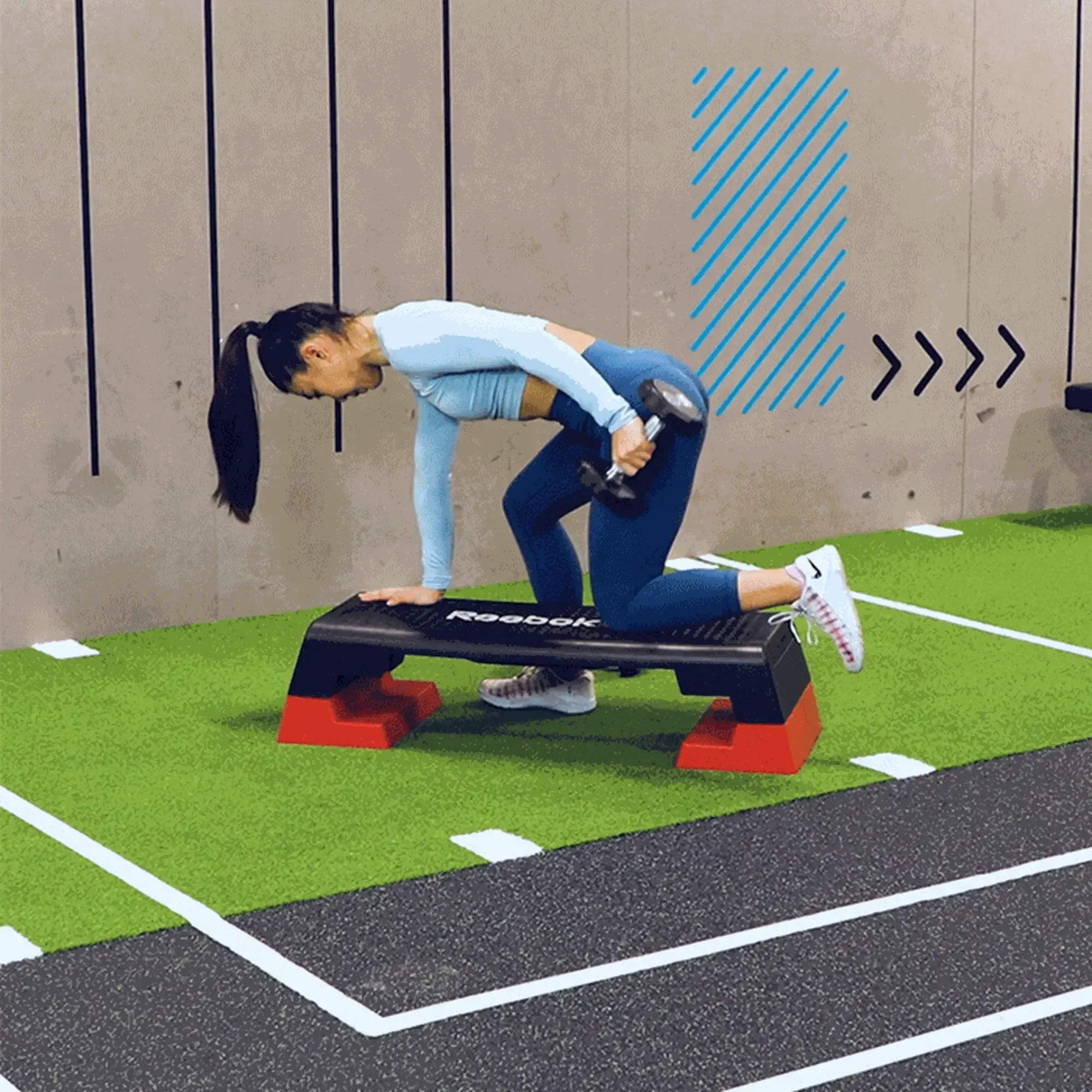 Woman in sportswear doing one-arm dumbbell row on a bench in gym