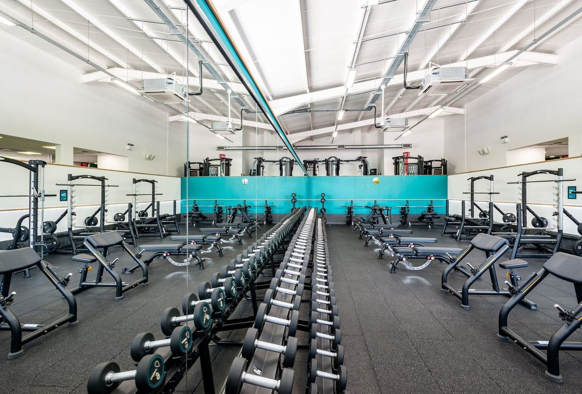 PureGym Northwich: Rows of treadmills, bikes, and weight machines with turquoise accents lining a bright gym interior.