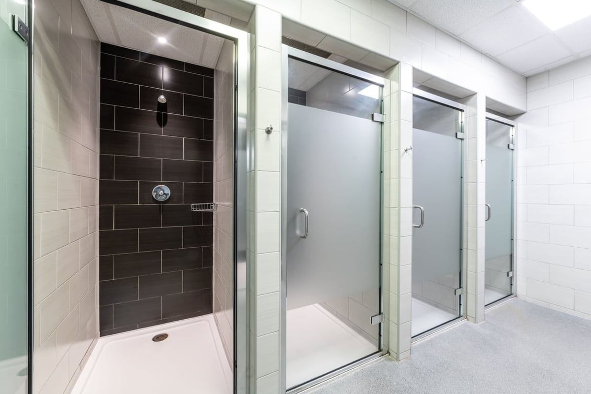 PureGym Harrogate: Shower stalls lined up in a tiled bathroom facility.