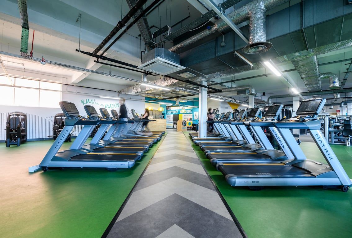 PureGym London Camden: Rows of treadmills and other cardio machines in a brightly lit gym space with exposed ductwork.