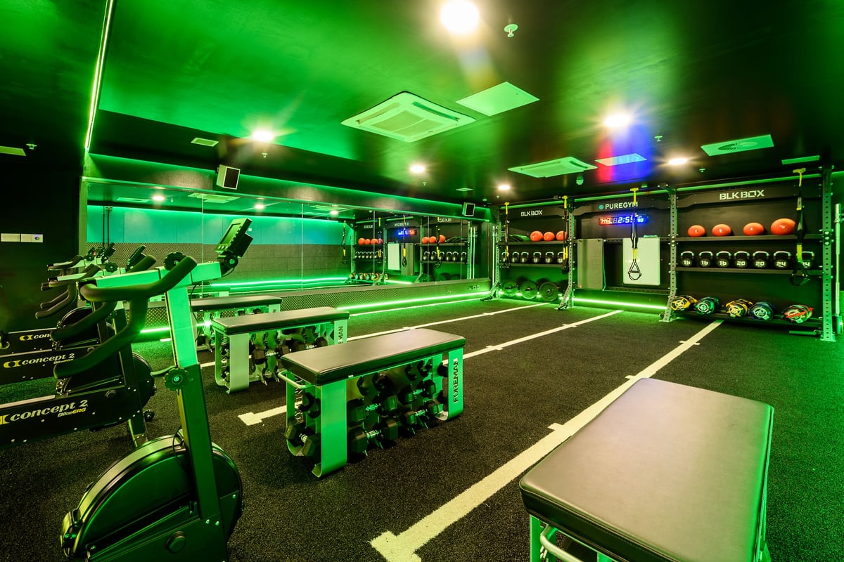 PureGym London Moorgate: Rows of green-lit weight racks, benches, dumbbell stands, and rubber flooring.