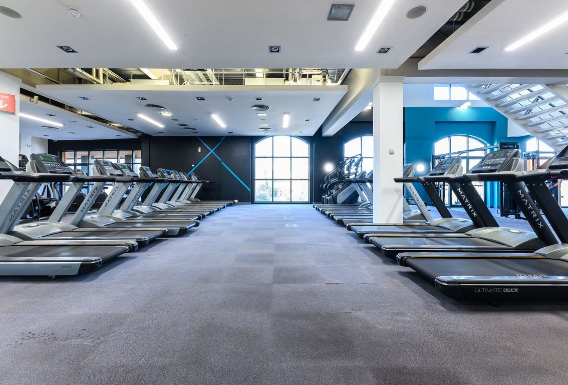PureGym Norwich Riverside: Rows of treadmills and elliptical machines in a modern gym interior with blue accents.