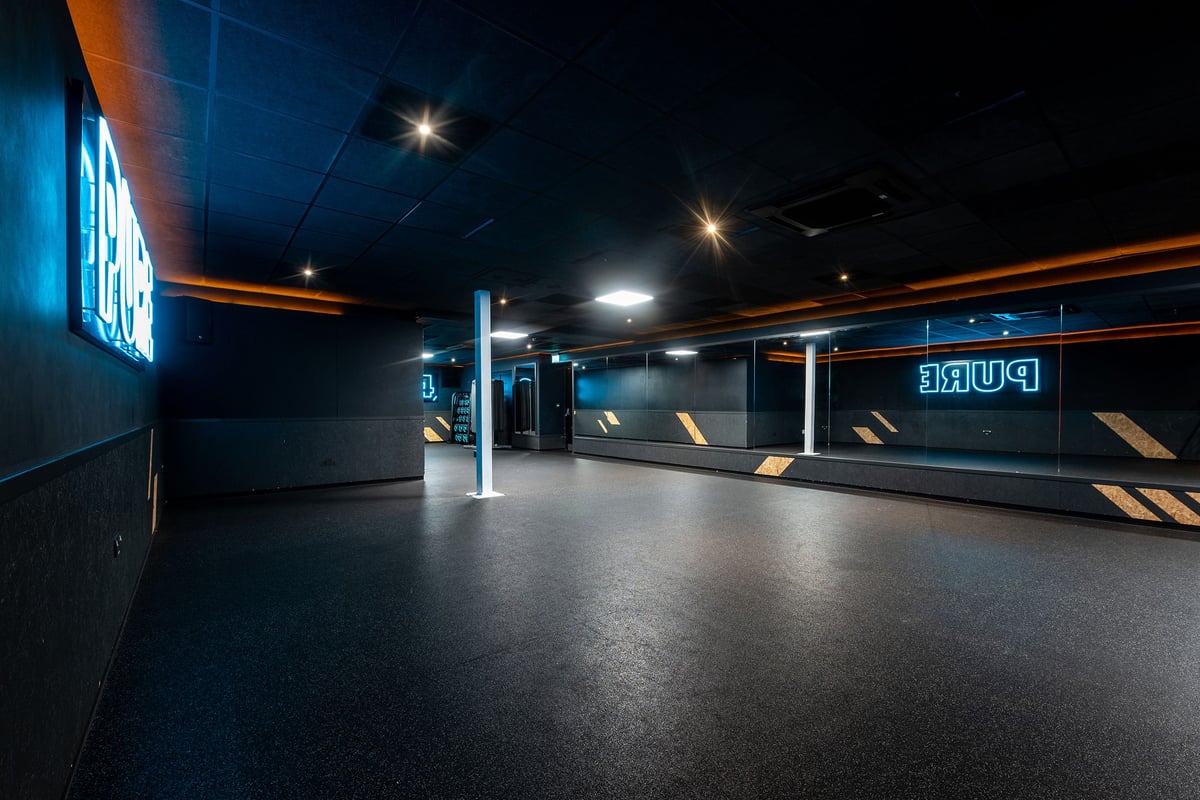 PureGym Southampton Central: Long hallway corridor, dimly lit with blue and orange lighting, rubberized flooring.