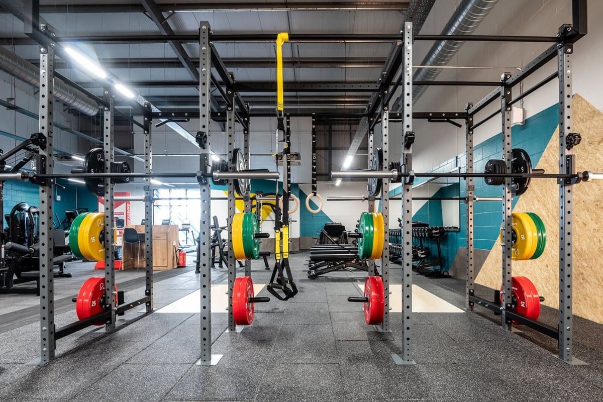 PureGym Lanark: Squat racks, weighted plates, kettlebells, suspension trainers, and rubberized flooring in a gym setting.