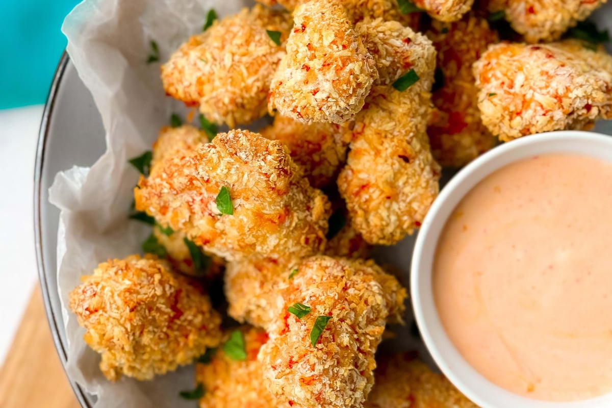 Crispy breaded chicken bites garnished with herbs served with creamy dipping sauce