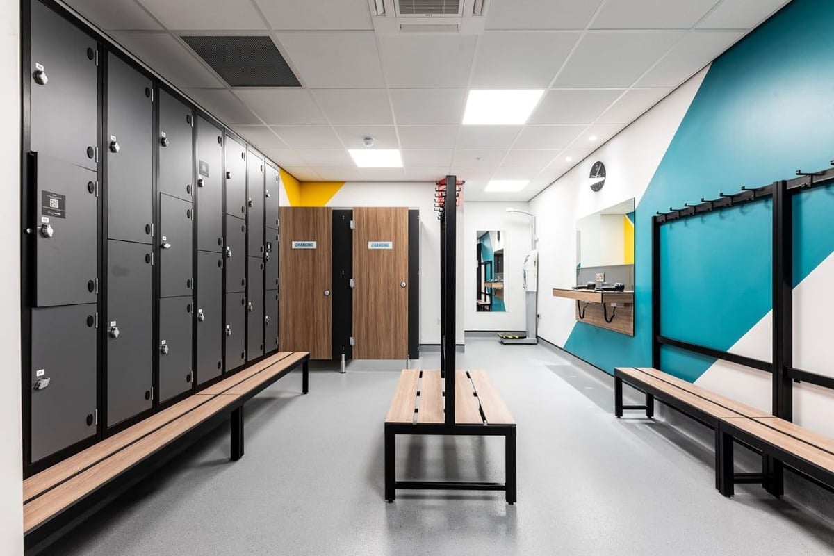 PureGym Tamworth: Lockers, benches, and rubberized flooring inside a changing room area.