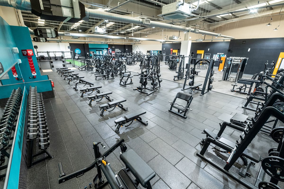 PureGym Weston-super-mare: Rows of stationary bikes, weight machines, free weights and benches in a commercial gym setting.