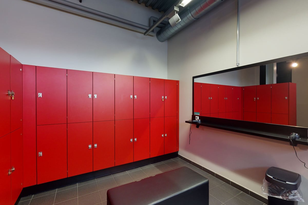 PureGym Oftringen: Red lockers, benches, and mirrored wall.