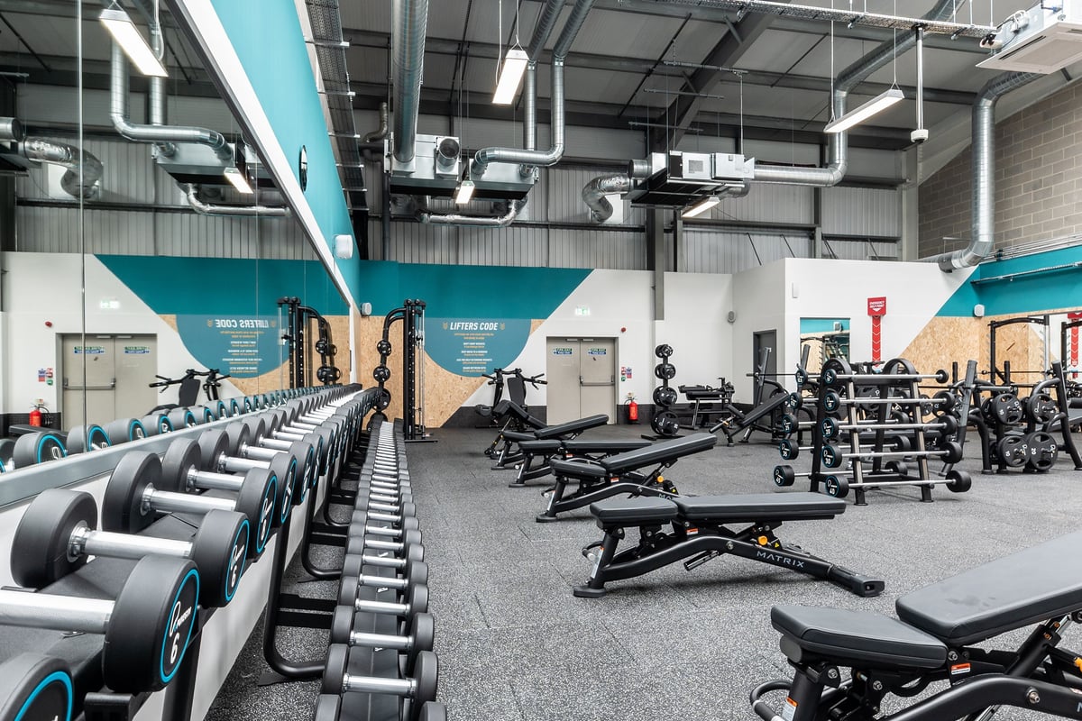 PureGym Sittingbourne: Rows of exercise bikes, benches, free weights, and resistance machines on rubberized gym flooring.