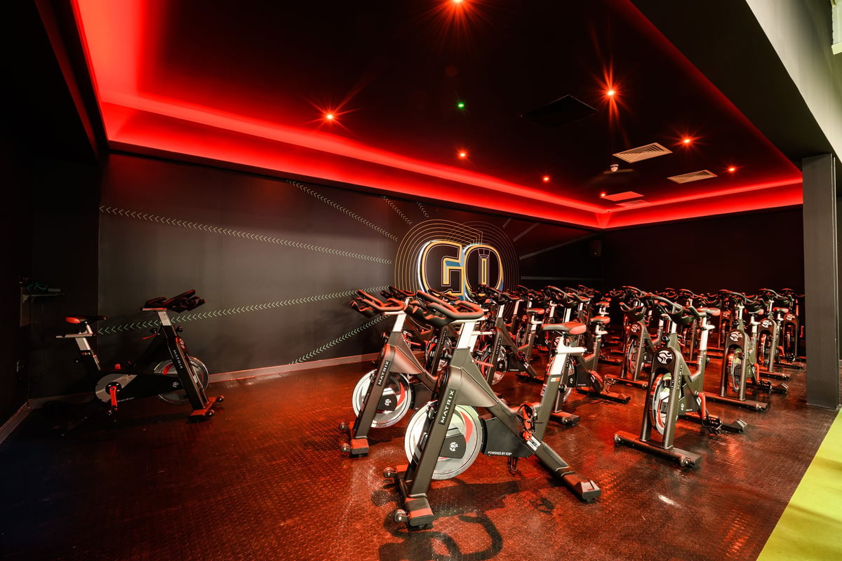 PureGym Telford: Rows of spin bikes in a dimly lit room with red ambient lighting.