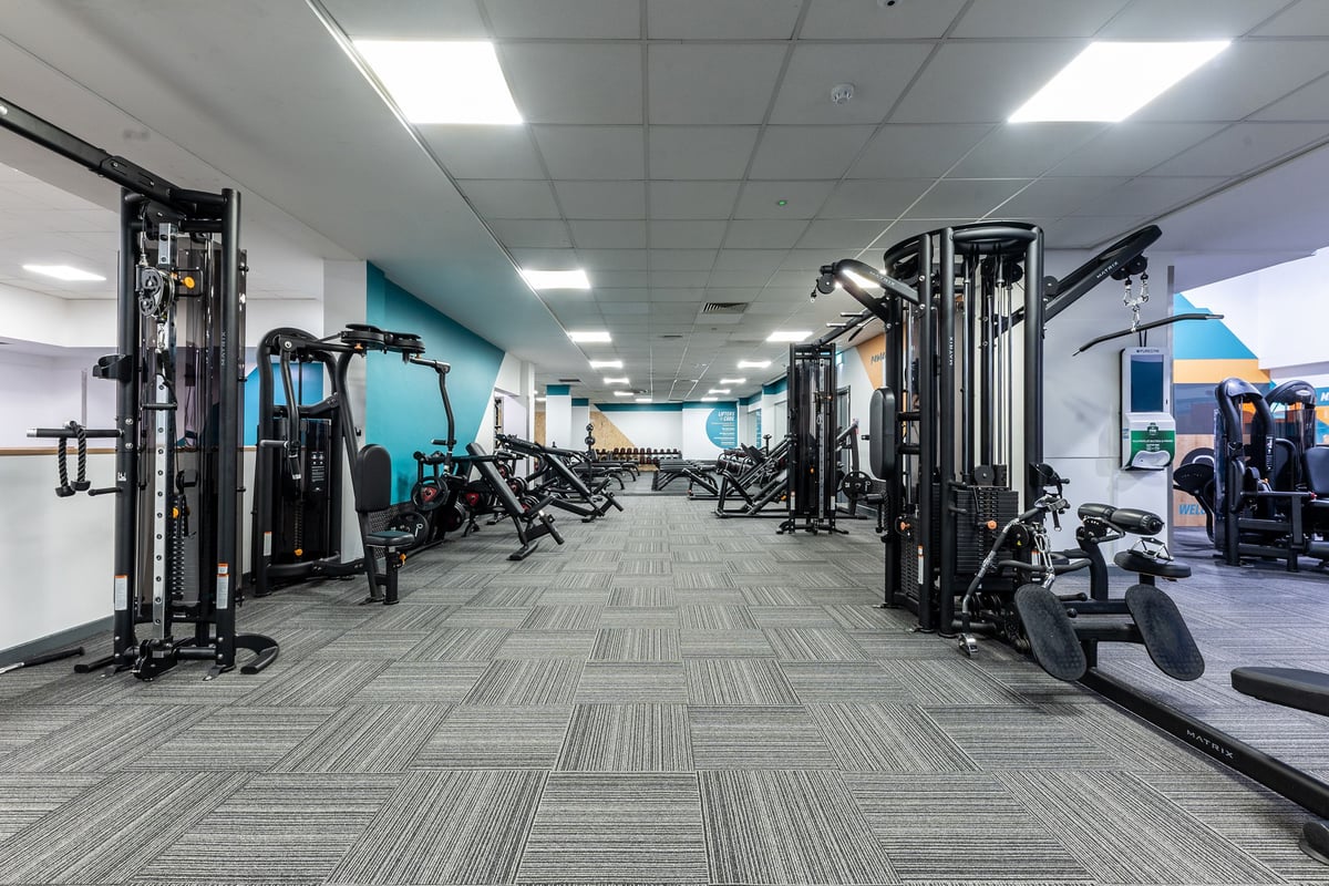 PureGym Purley: Rows of weight machines, cable crossovers, benches, and rubberized flooring in a modern gym studio.