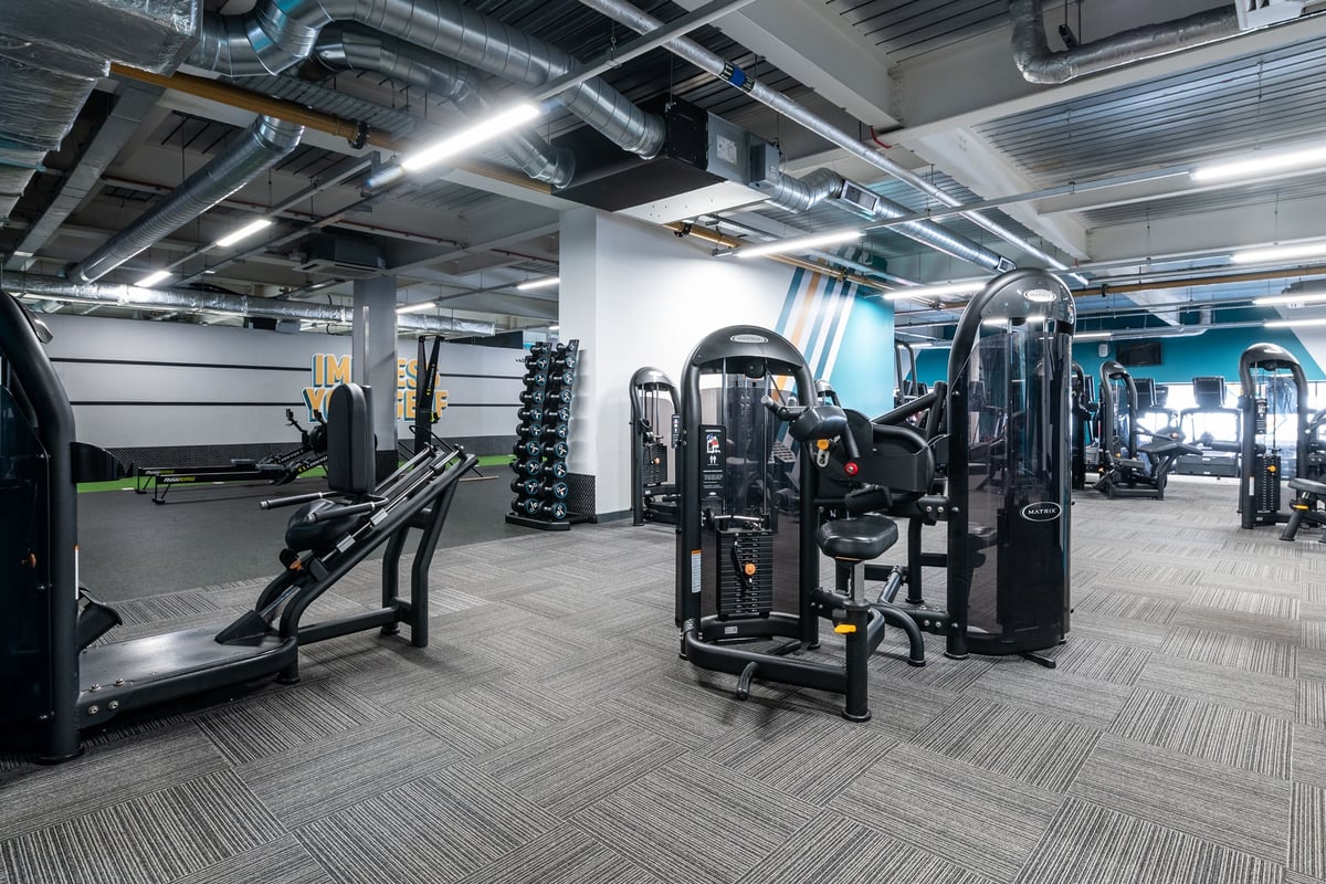 PureGym London Orpington Central: Weight machines, free weights, benches, and rubberised flooring in a fitness studio.