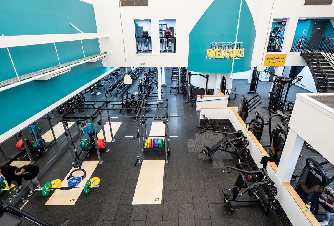 PureGym Belfast Boucher Road: Rows of weight machines, benches, free weights, and mirrored walls in a modern gym setting.