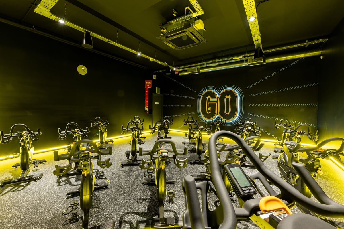 PureGym Tamworth: Stationary bikes, electronic displays, neon lighting in a cycling studio.