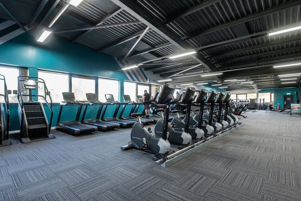 PureGym Milton Keynes Winterhill: Rows of treadmills, exercise bikes, and industrial-style flooring in a modern gym setting.