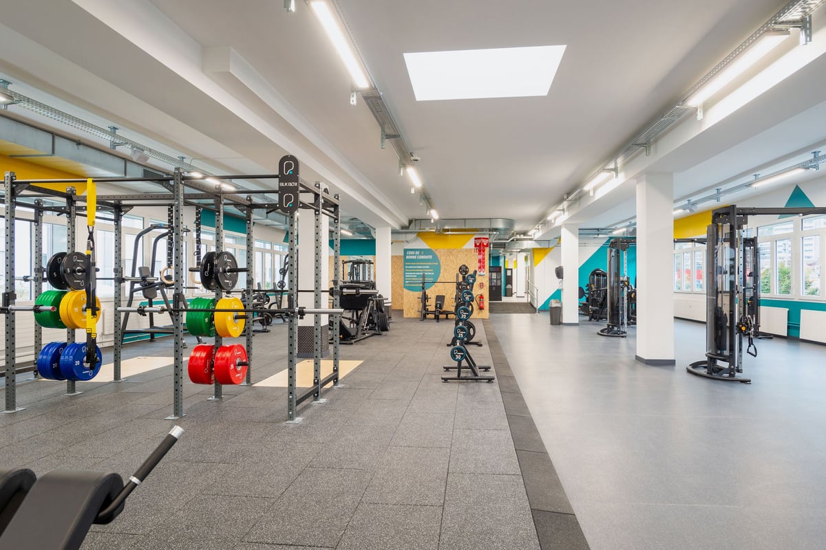 PureGym Vevey: Salle de sport avec appareils de résistance, haltères, haltères colorées, miroirs et sols caoutchoutés.