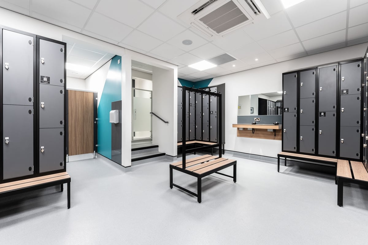 PureGym Knaesborough: Changing room with lockers, benches, and partitioned shower cubicles.