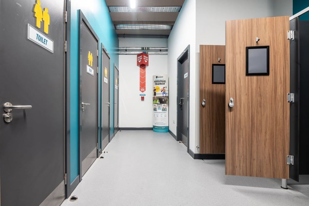 PureGym Lanark: Corridor with doors leading to changing rooms, toilets demarcated with color-coded signage.