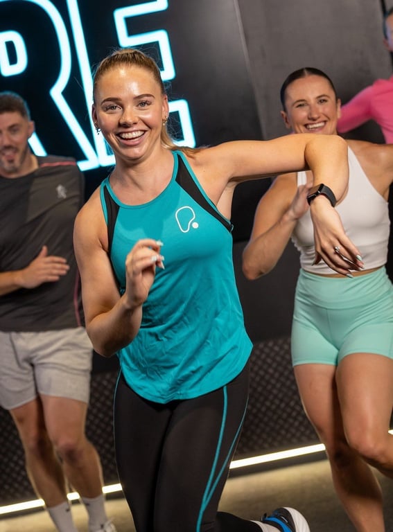 PureGym: a smiling female gym trainer and two smiling members