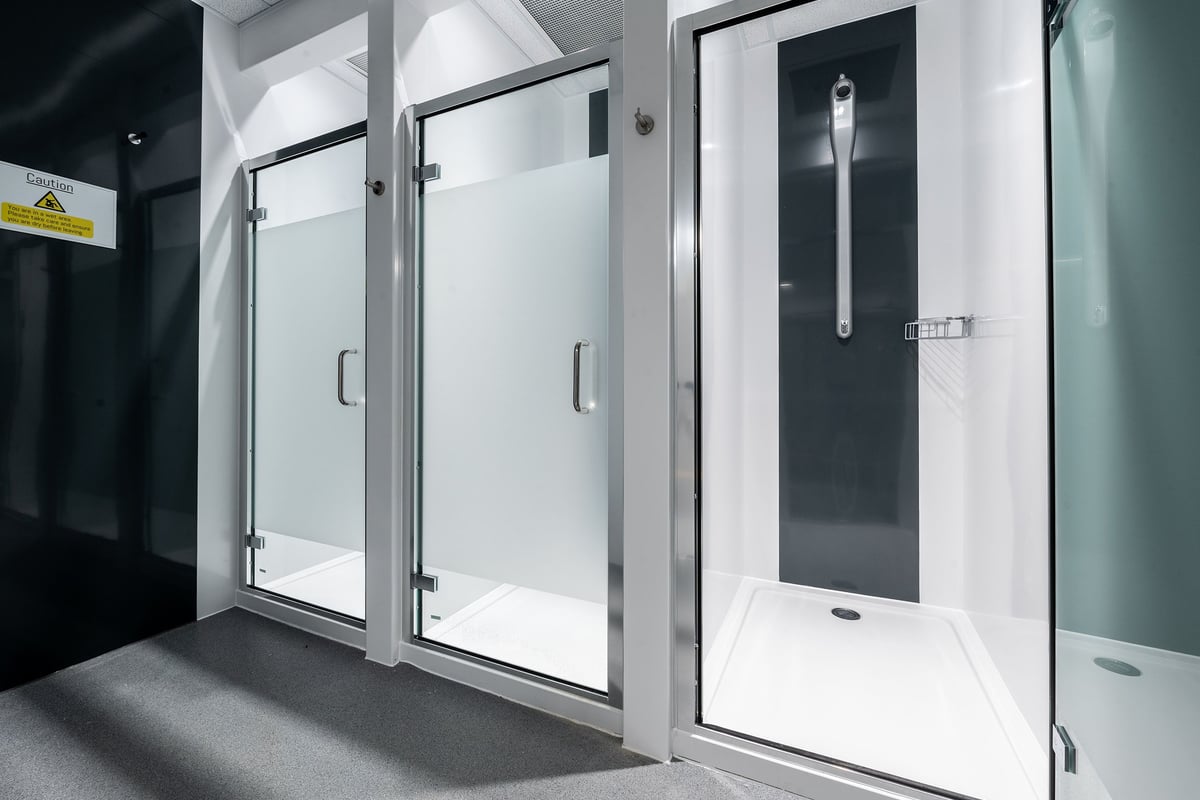 PureGym Chelmsford Meadows: Shower and changing cubicles with glass doors and tiled floors.
