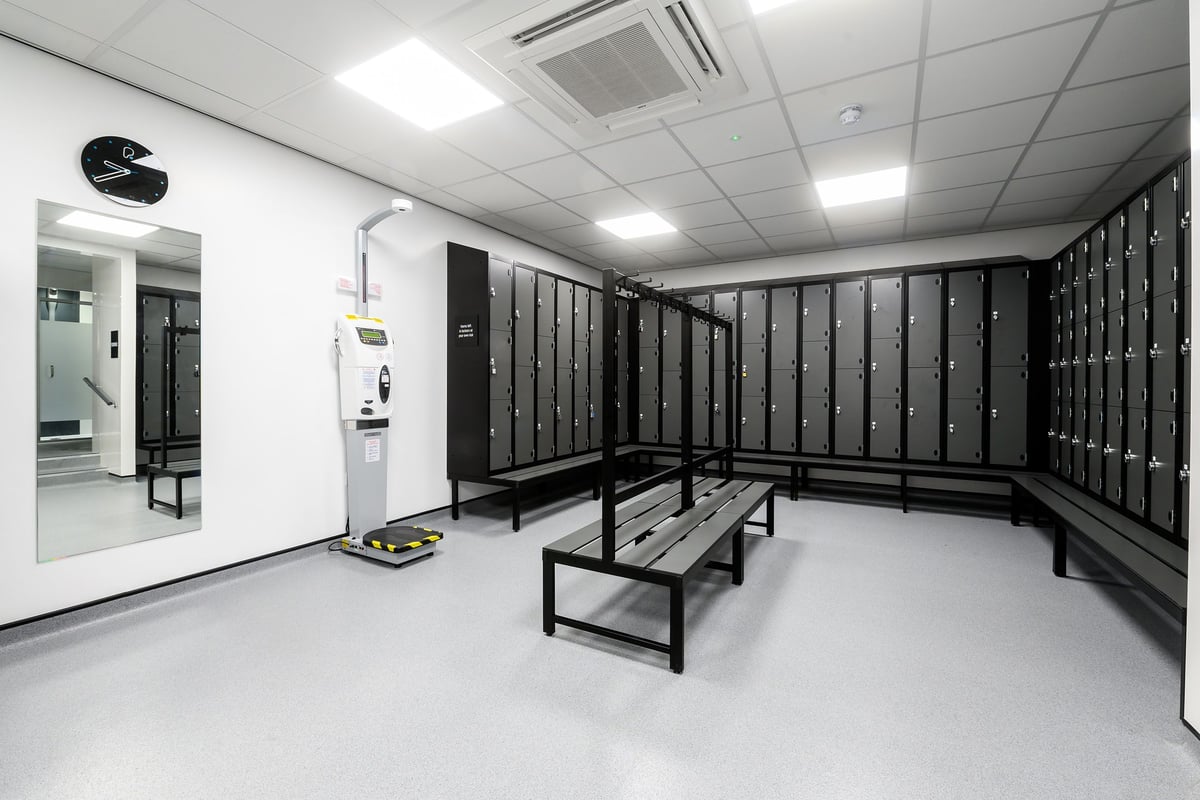 PureGym Bristol Abbey Wood Retail Park: Changing room benches, lockers, and automated shoe cleaning station.