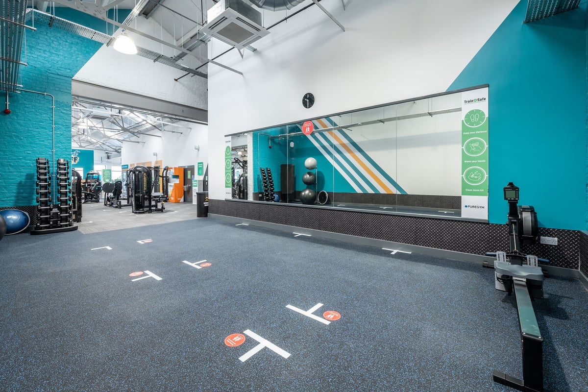 PureGym Puregym Crayford: Rows of racks with weights, balls, and cardio equipment in a turquoise and grey gym interior.