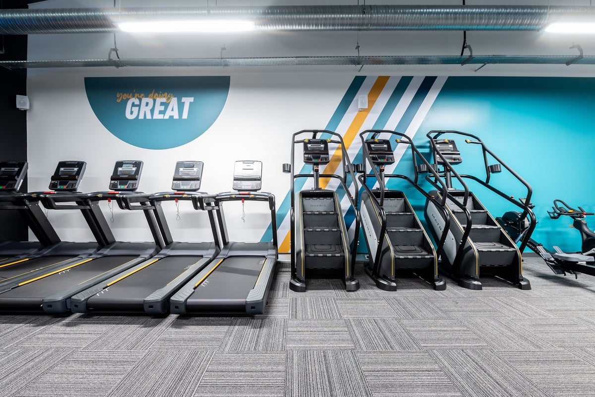 PureGym Letchworth: Rows of treadmills, inscribed "GREAT", alongside strength training equipment in a modern fitness space.
