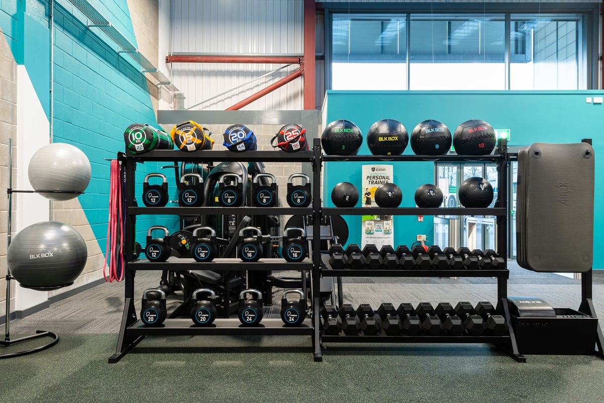 PureGym Elgin: Rows of kettlebells, medicine balls, weight plates, and dumbbell racks in a gym space.