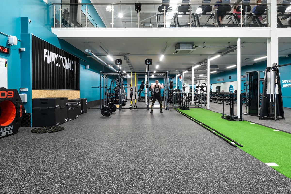 PureGym Exeter Bishops Court: Functional training area with resistance machines, turf, free weights, and mirrors along walls.