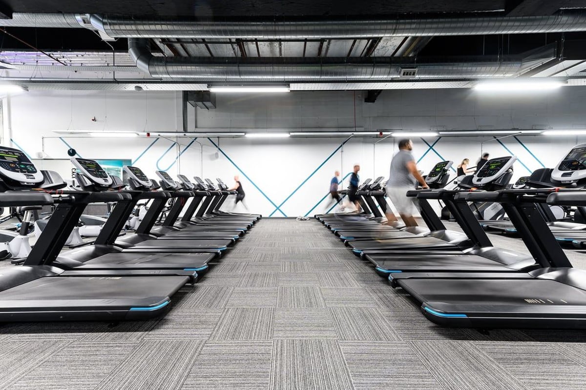 PureGym Hemel Hempstead: Rows of treadmills inside a bright gym space with blurred figures exercising.