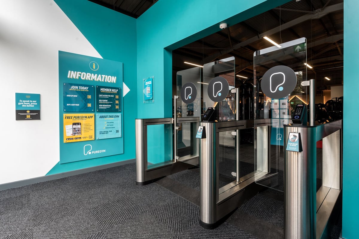 PureGym Spalding: Turnstiles, information signs, and waiting area at a gym reception.