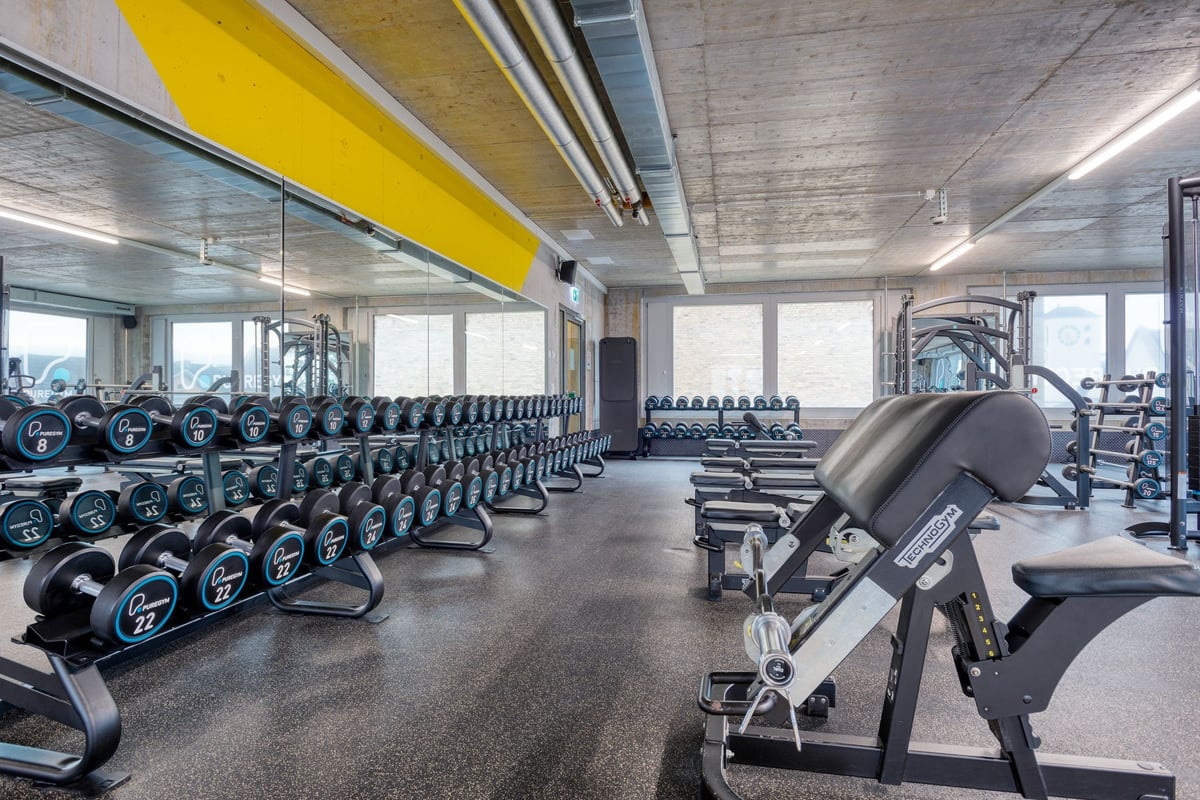 PureGym Lenzburg : une salle de sport avec des haltères, des appareils de musculation et un studio avec du