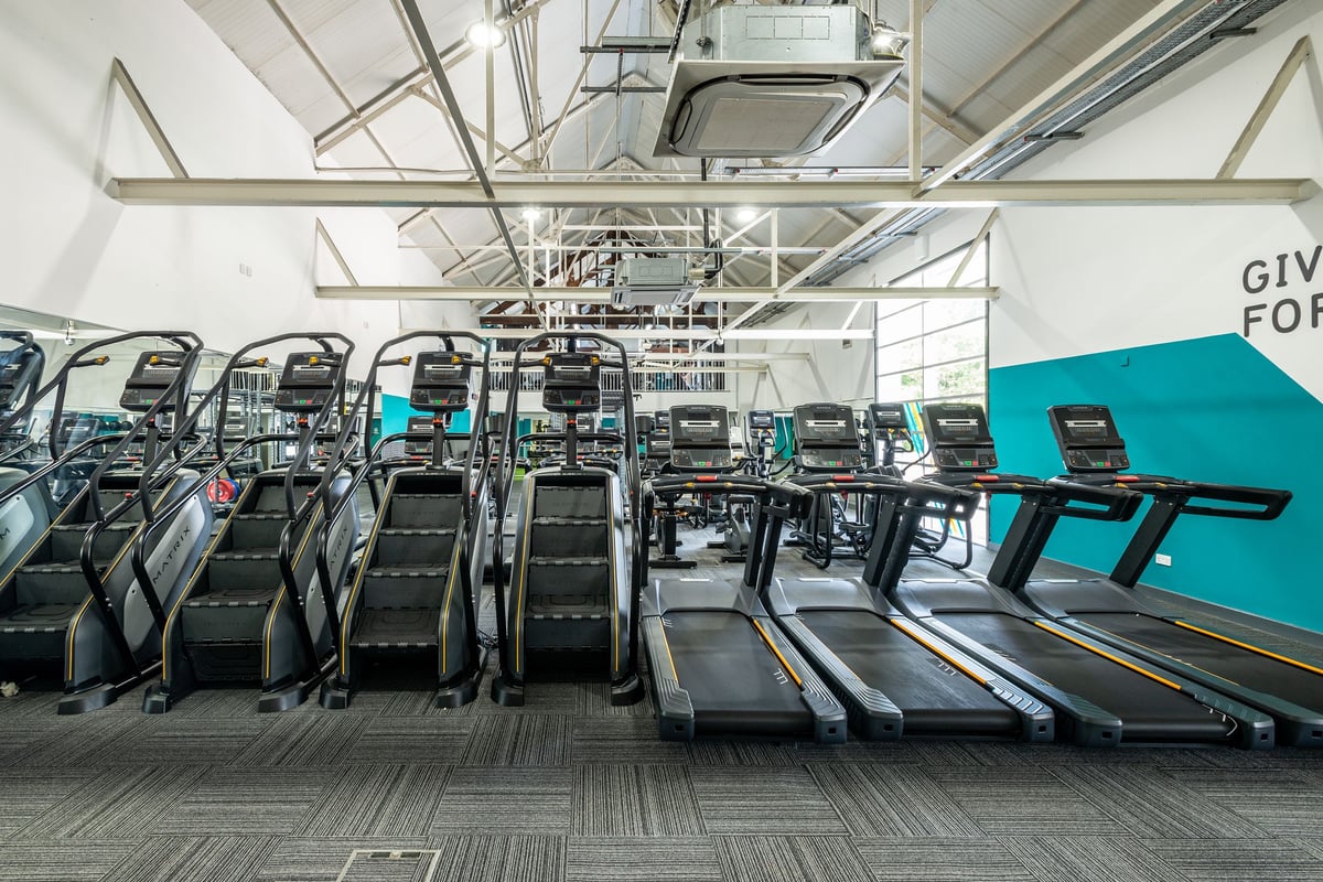 PureGym Northwich: Rows of treadmills and other cardio machines in a gym setting with high ceilings.