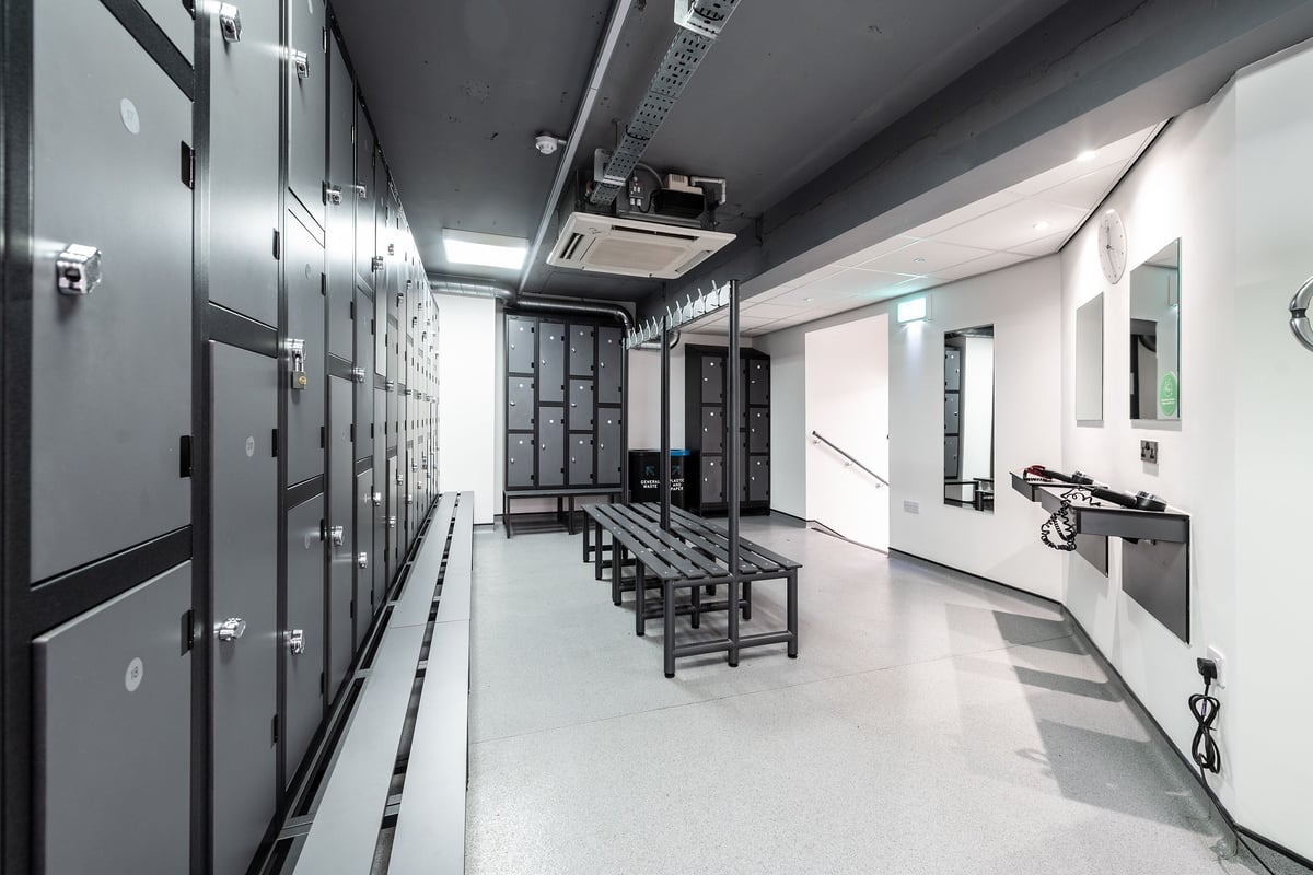 PureGym London Sydenham: Rows of lockers, benches in the middle, exercise equipment along the walls.