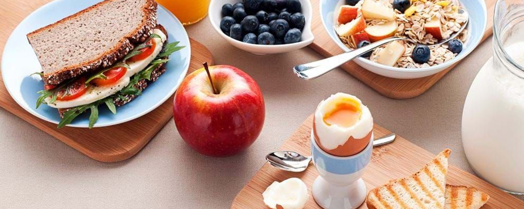 Sandwich, boiled egg, toast, apple, blueberries, muesli with fruit, orange juice, and milk