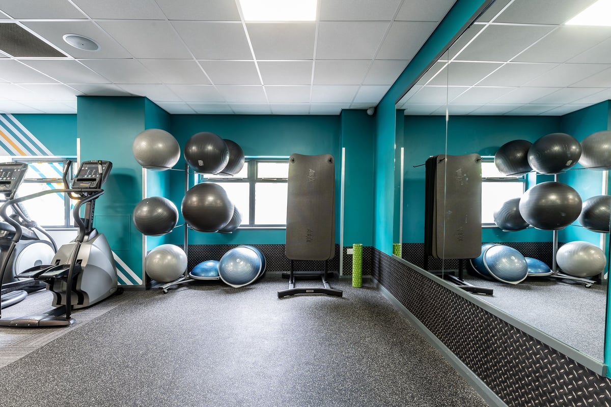 PureGym Woking: Exercise studio with stability balls, medicine balls, and rubberized flooring in turquoise hues.