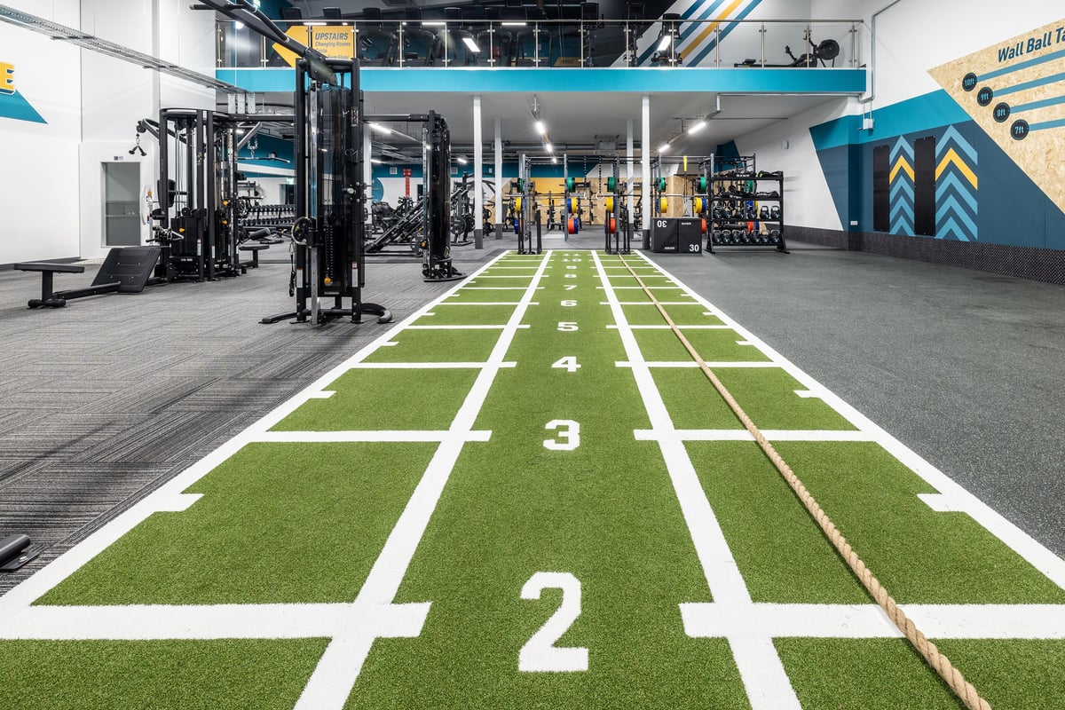 PureGym Hull Clough Road: Turf track with yardage markers, weight racks, and exercise equipment.