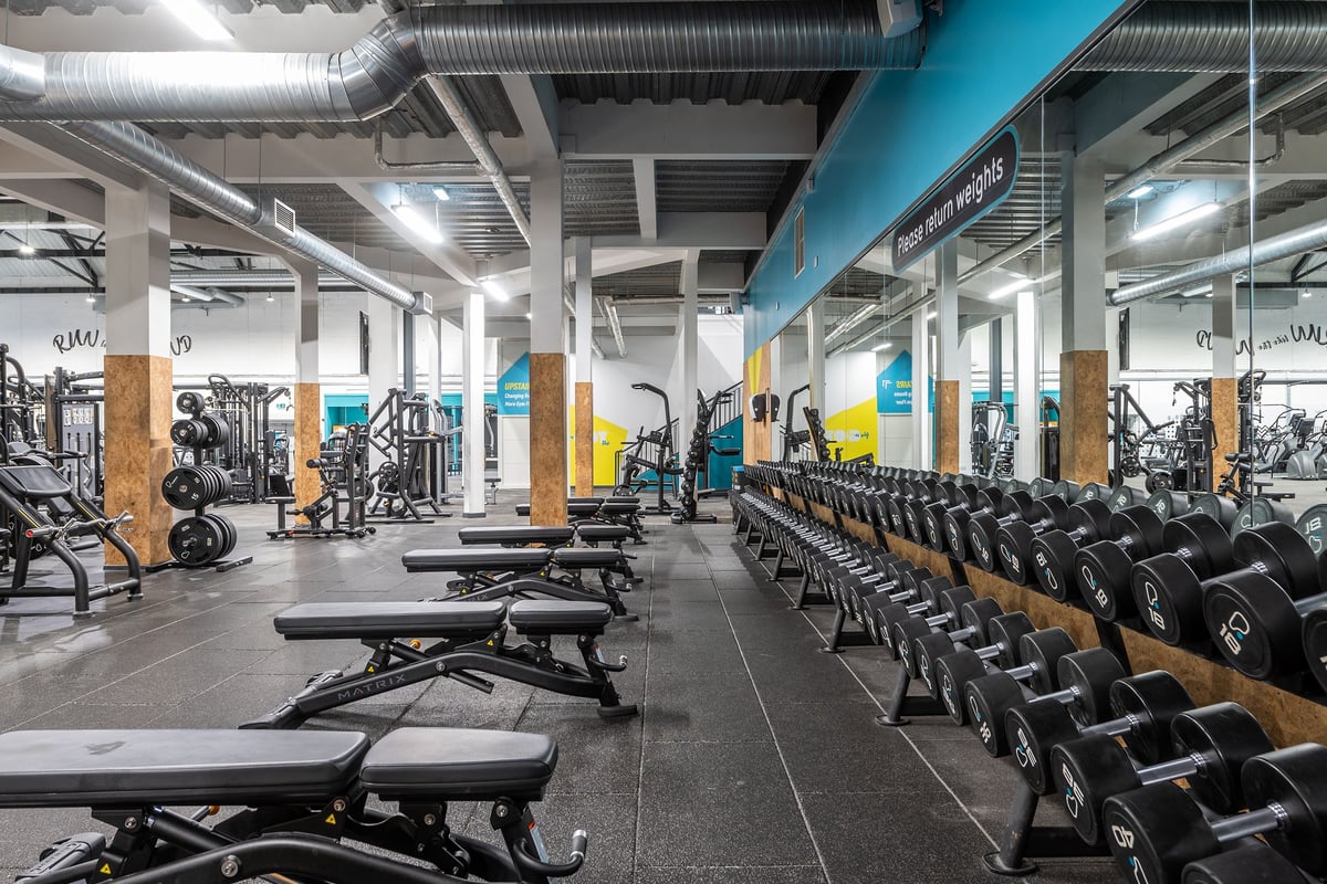 PureGym York: Gym floor with weight training equipment, benches, racks, dumbbells, and a vibrant colour scheme.