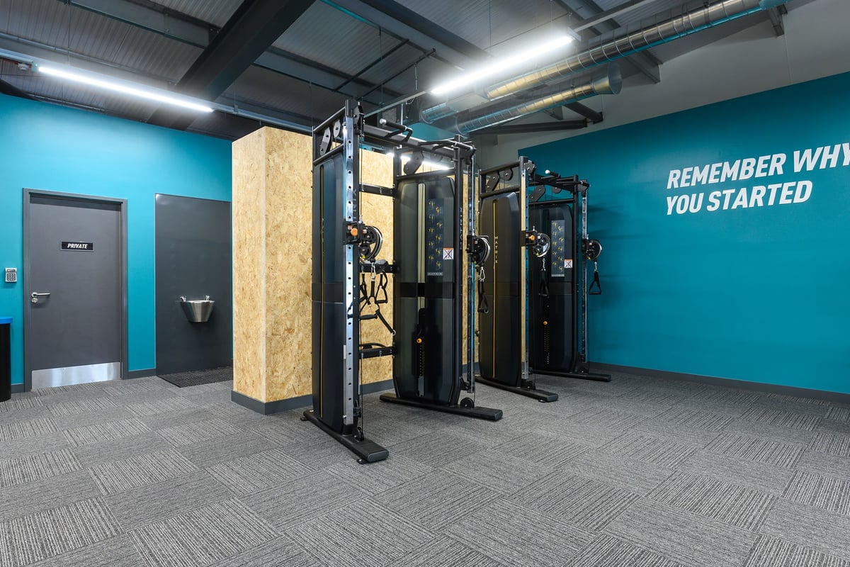 PureGym Barnstaple: Weight machines, heavy duty racks, teal wall with motivational text, open concept gym floor.