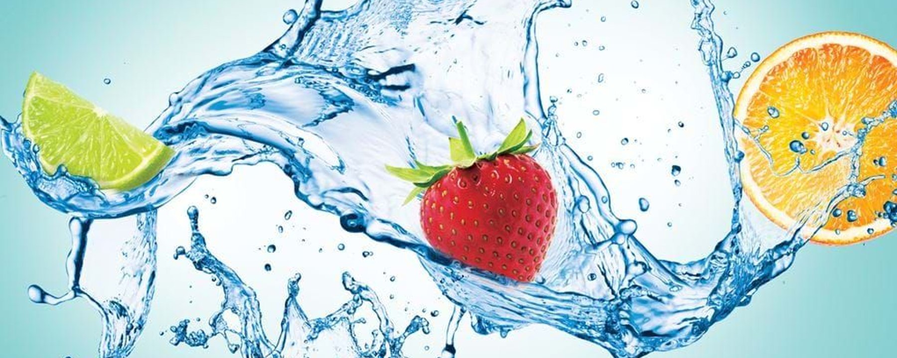 Splashing water with lime wedge, strawberry, and orange slice on blue background
