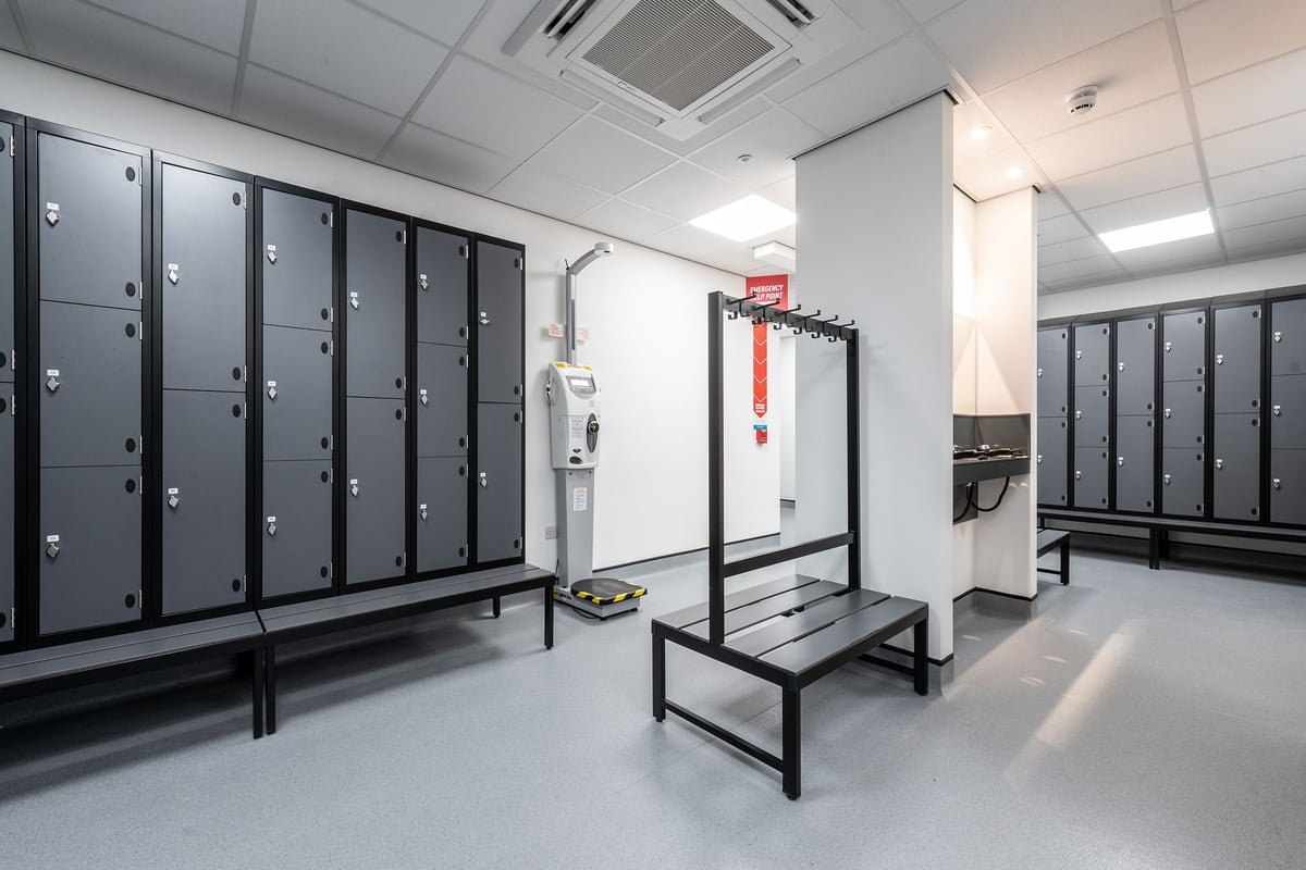 PureGym Durham Arnison: Rows of lockers, benches, and open shower area typical of a gym changing room.