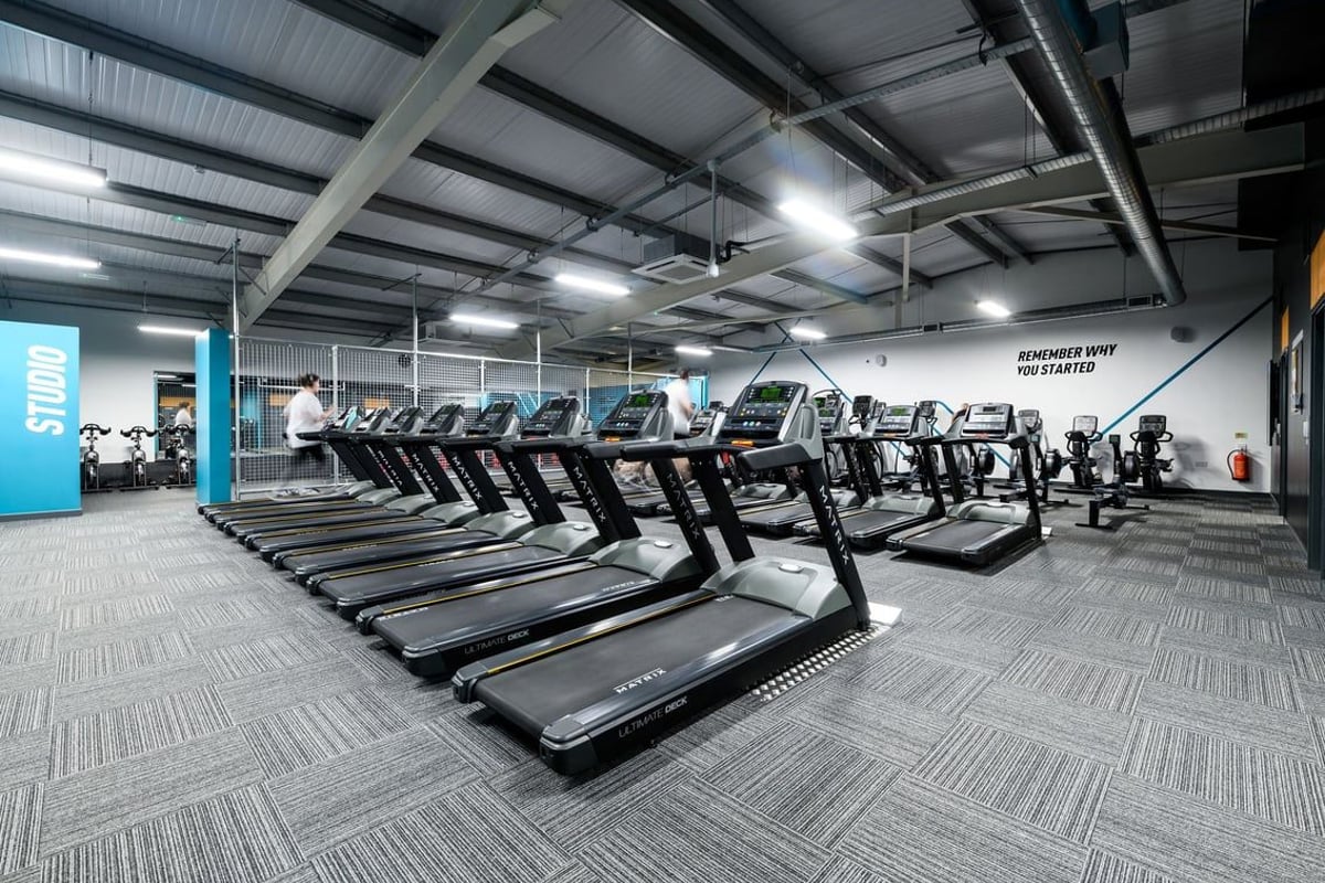 PureGym Swindon Mannington Retail Park: Rows of treadmills in a well-lit gym interior with exposed ceiling beams.