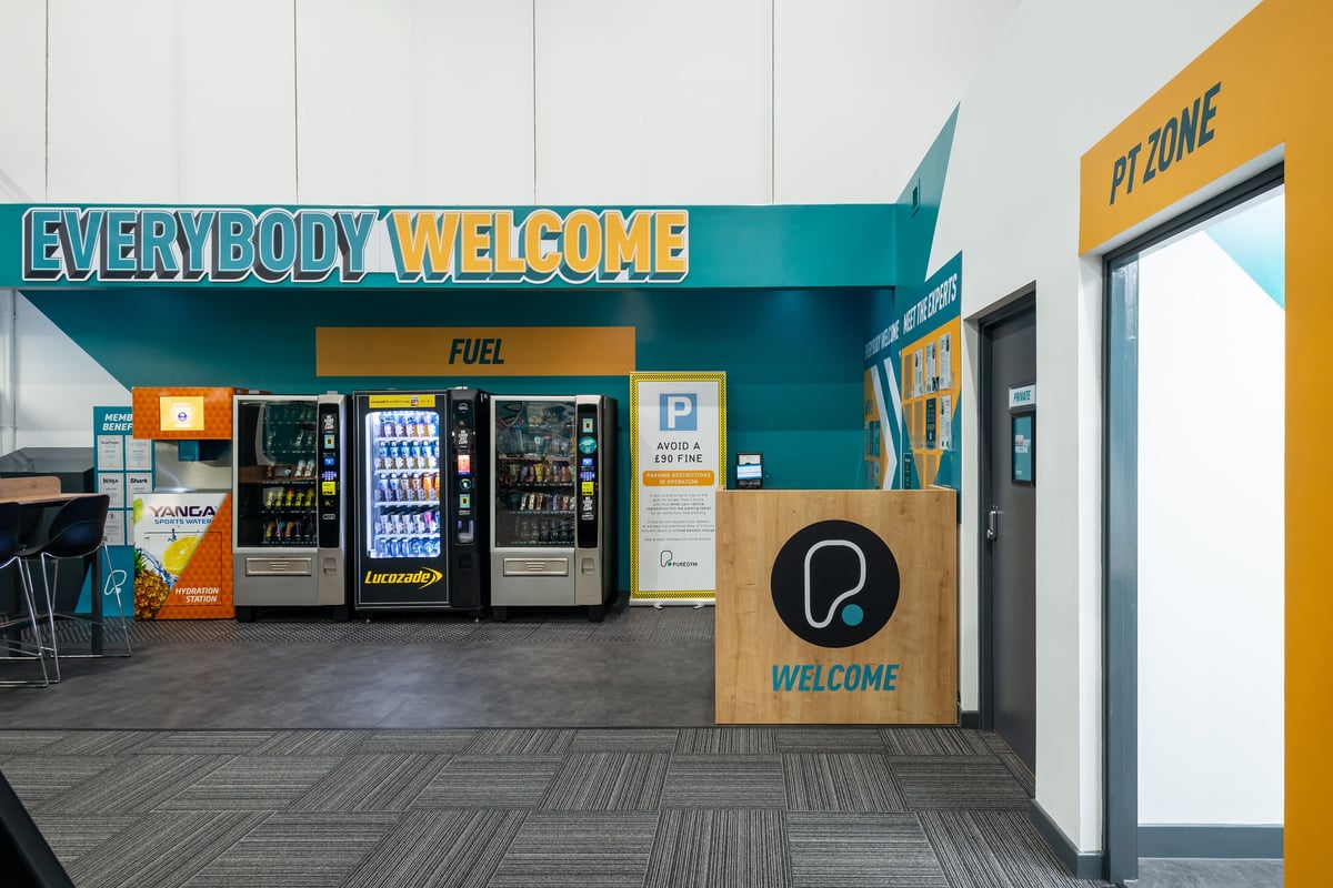 PureGym Wrexham: Vending machines, signage reading "Everybody Welcome", and "Welcome" sign.
