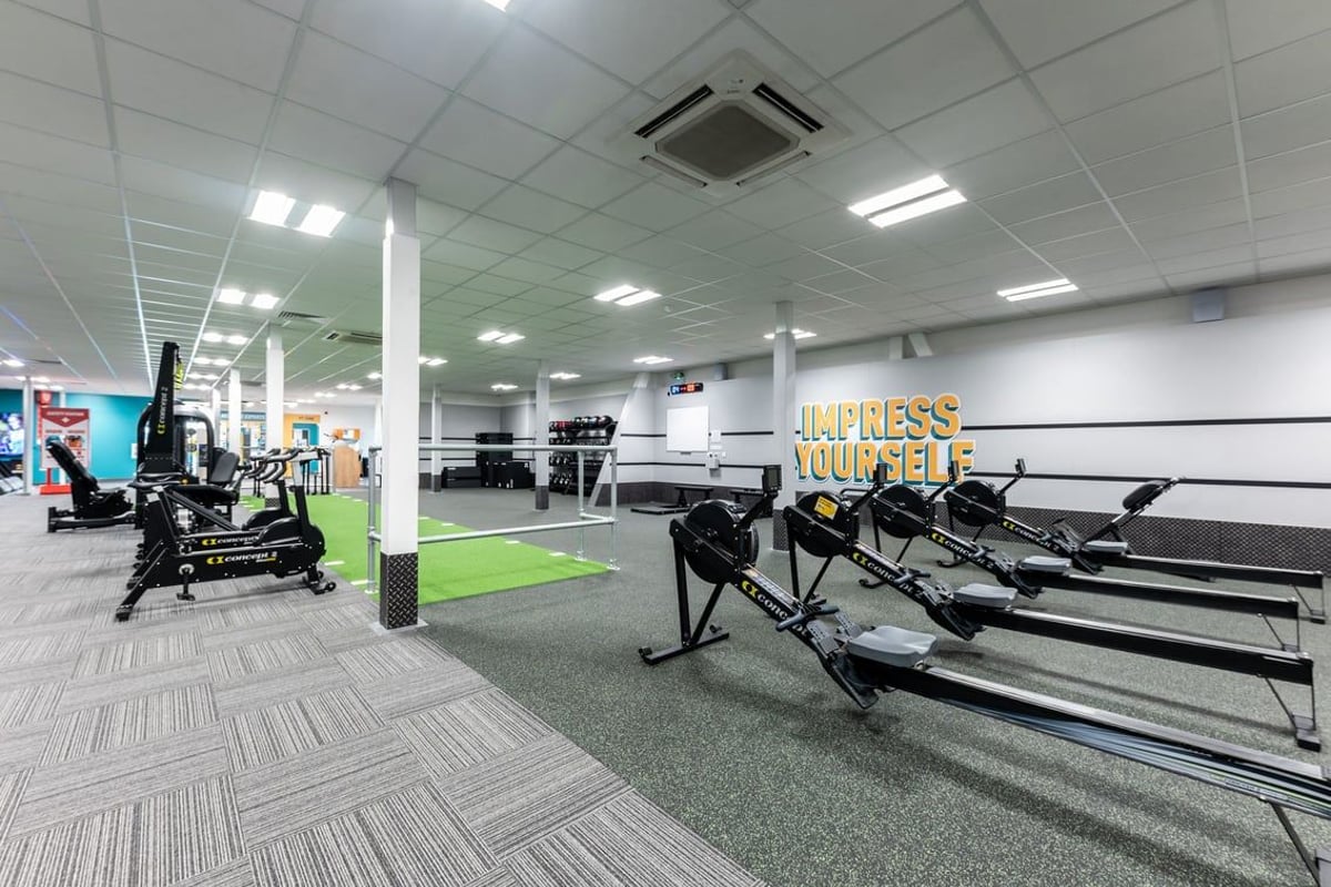 PureGym Gloucester Retail Park: Free weights, resistance machines, rubberized flooring in a brightly lit gym studio.