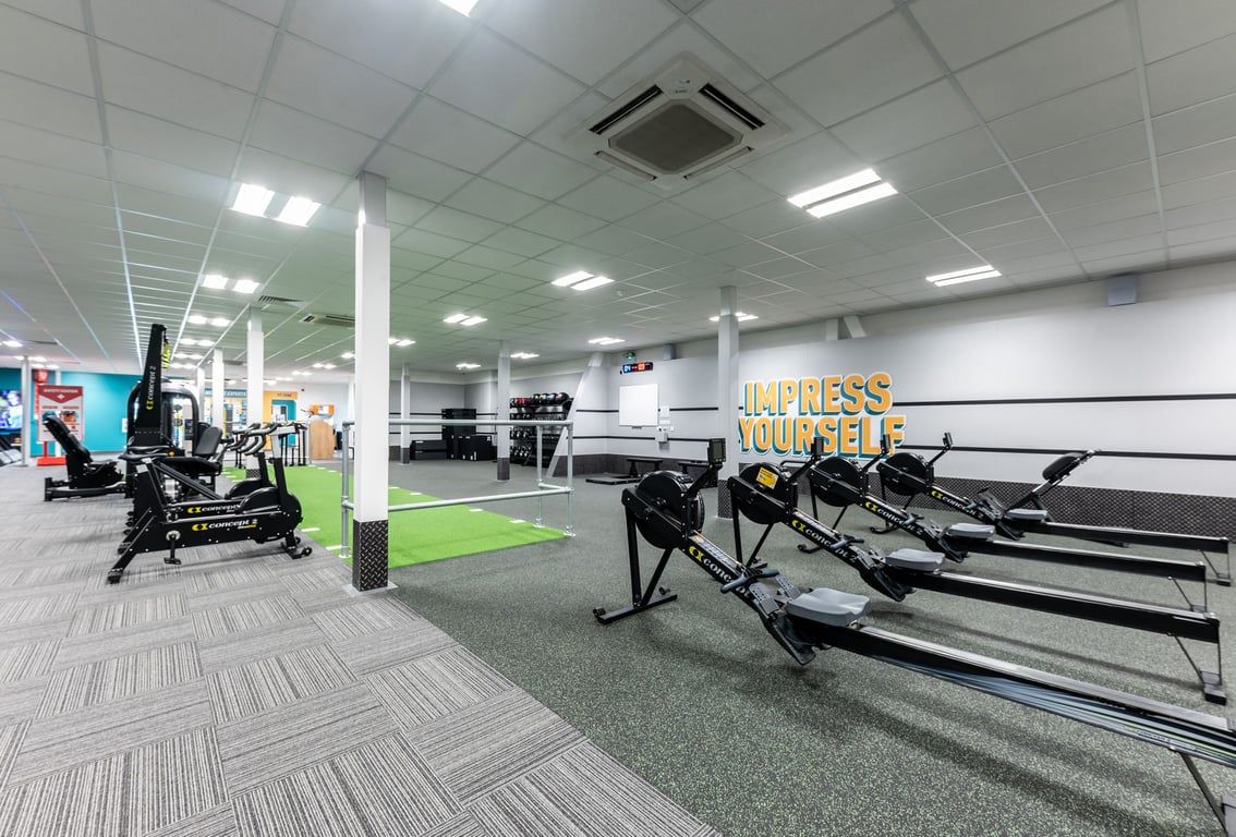 PureGym Gloucester Retail Park: Free weights, resistance machines, rubberized flooring in a brightly lit gym studio.