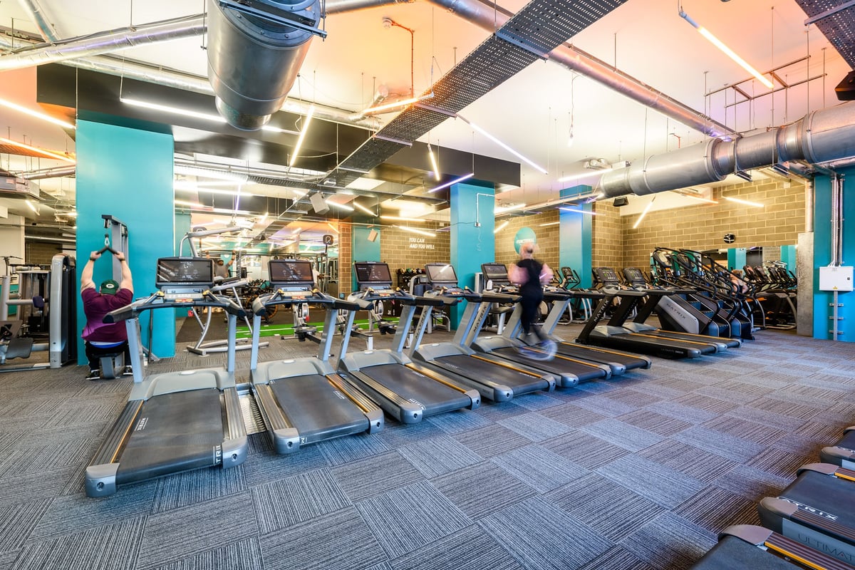 PureGym London Borough: Rows of treadmills, stationary bikes, and weight machines in an industrial-style gym interior.