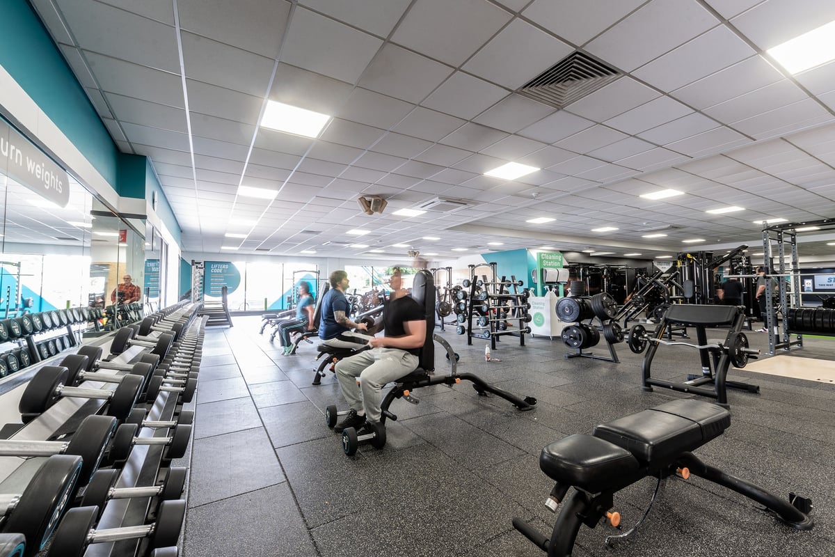 PureGym Woking: Weight racks, cardio machines, benches, and mirrored walls in a typical gym setting.