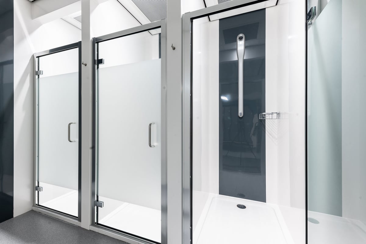 PureGym Watford Waterfields Retail Park: Glass shower stalls and entrance doors in a changing or locker room area.
