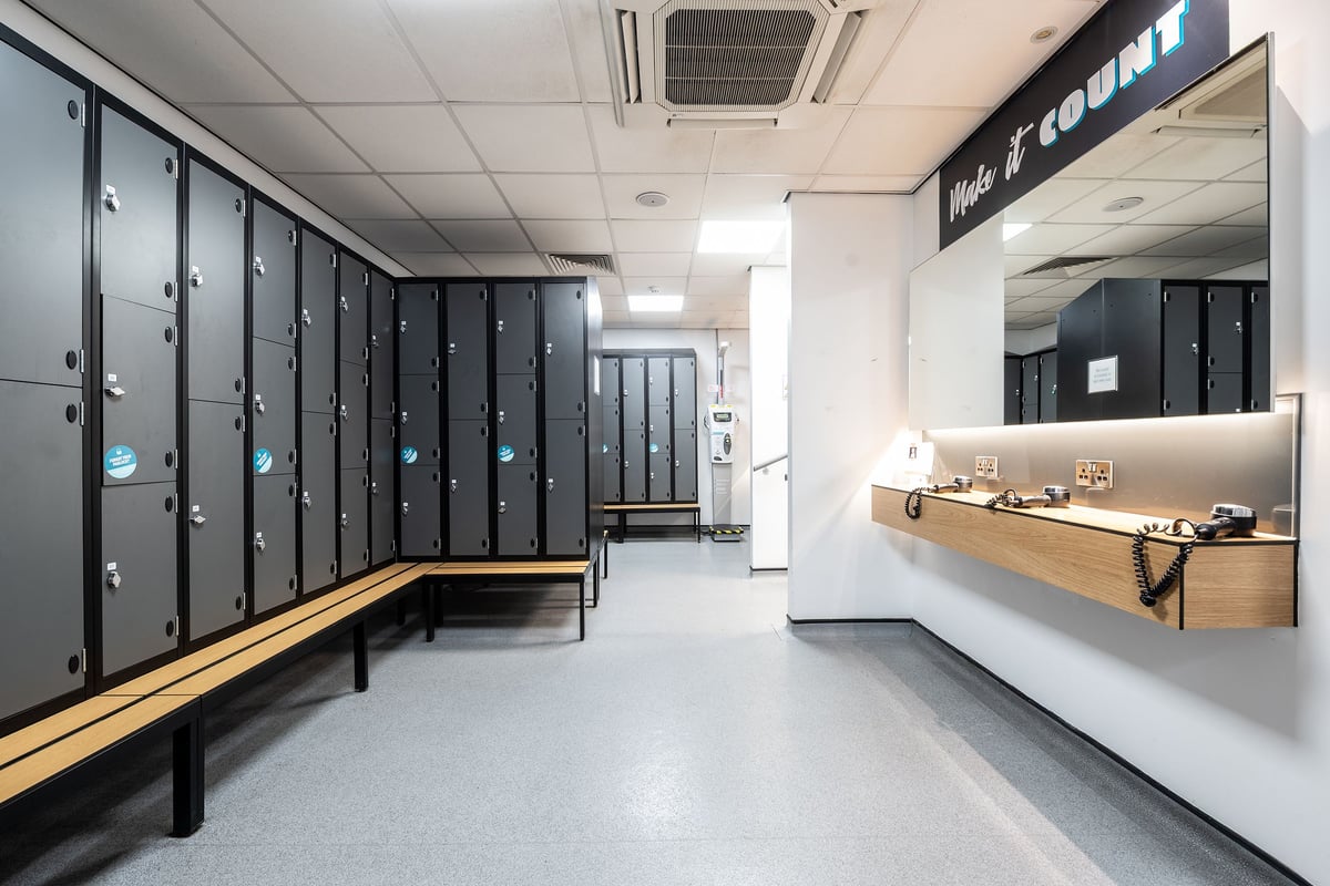 PureGym York: Rows of lockers, benches, and a counter in a fitness center changing room.